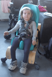 Ines sitting in her sitter seat mounted onto the mobile wooden base, for more movement